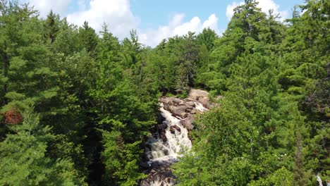 Aerial-view-of-a-stream-with-rapids-in-the-middle-of-a-forest,-Duchesnay-Falls,-Ontario