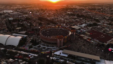 Aerial-view-tilting-over-the-Plaza-de-Toros-bullfighting-ring,-sunset-in-Mexico