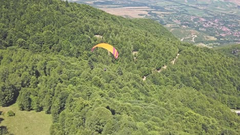 Paragliding-over-lush-green-mountain-landscape