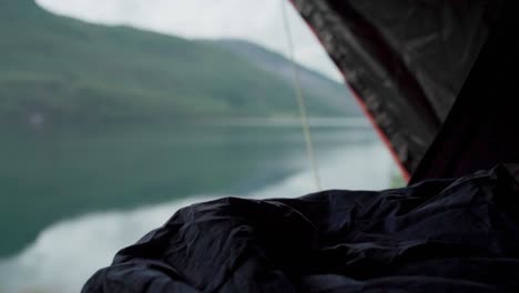 Person-Sleeping-Inside-Tent-Near-Mountain-Lake.-Handheld