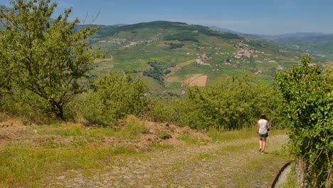 Pan-shot-with-girl-walking-through-wilderness-trail-in-Douro-Valley-in-Portugal