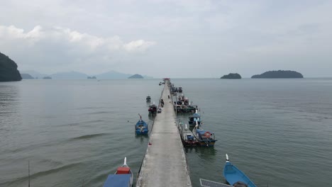 Low-POV-flight-along-floating-pier-of-moored-boats-in-Malaysian-sea