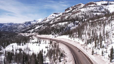 Toma-De-Drones-Del-Tráfico-En-Una-Carretera-Rural-En-Un-Paisaje-Nevado-En-Un-Soleado-Día-De-Invierno.