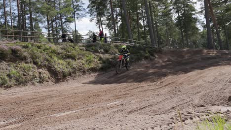 Ein-Motocross-Fahrer-Beschleunigt-Mit-Hoher-Geschwindigkeit-Aus-Einer-Berme-Auf-Einem-Dirtbike-In-Gnagardalen,-Schweden
