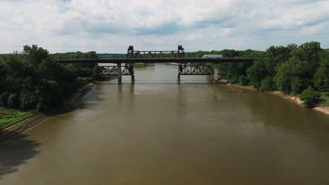 Camión-Conduciendo-Por-El-Puente-De-La-Autopista-Junto-Al-Viejo-Puente-Ferroviario-Oxidado-Que-Cruza-El-Río-Blanco-En-De-Valls-Bluff,-Arkansas