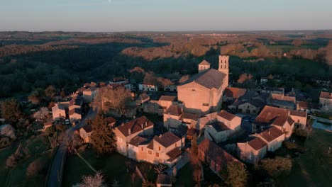 Wide-aerial-view-of-the-village-of-Saint-Avit-Ségnieur-and-its-church,-located-in-the-Dordogne-region,-a-magnificent-tourist-attraction-at-sunrise
