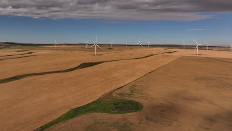 A-drone-flies-across-a-prairie-farmland-wind-farm-to-reveal-a-windmill-in-southern-Alberta,-Canada