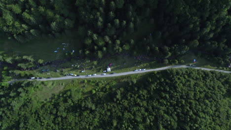 Aerial-view-of-a-campsite-nestled-in-the-valley,-featuring-a-off-road,-and-fir-green-forests-at-the-mountain