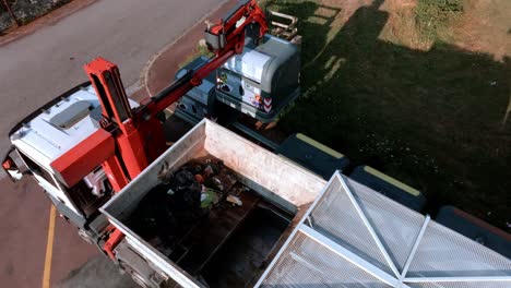 Müllwagen-Sammelt-Recyceltes-Glas-Aus-Behältern-Am-Straßenrand,-Hebt-Es-Hoch-Und-Entlädt-Es-Auf-Der-Ladefläche-Des-Lastwagens,-Glasrecyclingkonzept