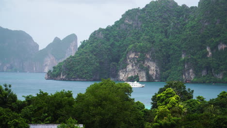 Yacht-Sailing-In-The-Ocean-Surrounded-By-Limestone-Cliffs-In-Koh-Phi-Phi-Island,-Thailand