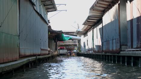 Der-Bootsmann-Manövriert-Das-Holzboot-Mit-Einer-Gruppe-Touristen-Im-Kanal-Des-Beliebten-Touristenziels-In-Thailand,-Dem-Schwimmenden-Markt-Damnoen-Saduak