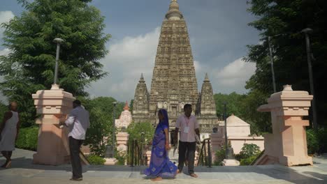 Buddhist-monks-at-the-Mahabodhi-Mahavihara-complex,-Temple-building-facade,-Devotees-and-tourists-at-Mahabodhi-temple-in-daylight,-Wide-shot
