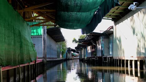 An-Den-Seiten-Des-Schwimmenden-Marktes-Damnoen-Saduak-In-Thailand-Sind-Geschlossene-Souvenirläden-Zu-Sehen,-Während-Die-Touristen-Eine-Langsame-Und-Gemütliche-Bootsfahrt-Unternehmen