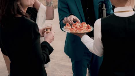 Slow-motion-shot-of-a-waiter-serving-canapes-to-guests-at-a-luxury-wedding