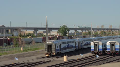 Montreal-Réseau-Express-Métropolitain-REM-Zug,-Der-Während-Der-Goldenen-Stunde-Auf-Einer-Hochstrecke-An-Mehreren-Angehaltenen-Exo-Nahverkehrszügen-Vorbeifährt