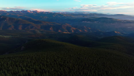 Cinematic-aerial-drone-sunrise-morning-sun-flare-high-Denver-front-range-foothills-Rocky-Mountains-layers-i70-Idaho-Springs-Evergreen-Mount-Evans-14er-wilderness-Squaw-pass-Echo-Mountain-backwards-pan