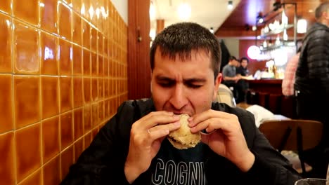 Man-eating-a-prego-for-dinner-at-a-restaurant,-traditional-sandwich-from-Porto