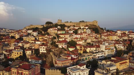 Aerial-pull-back-and-reveal-ancient-fortress-on-a-hill-with-traditional-architecture-in-Kavala,-Greece