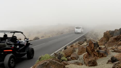 White-van-and-buggy-ridding-on-asphalt-road-on-foggy-day,-Teide,-Tenerife