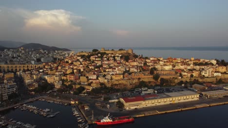 Aerial-establishing-of-picturesque-hill-with-ancient-fortress-and-Roman-aqueduct-in-Kavala,-Greece-at-sunset