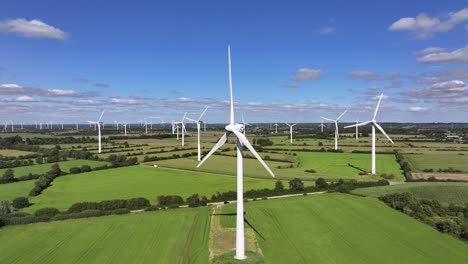 Wind-turbines-farming-wind-energy,-green-fields,-blue-sky,-countryside,-sunny,-slow-pull-in-movement,-symbolic,-picturesque