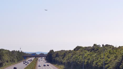 Airplane-takes-off-into-sky-above-M1-motorway,-view-from-Feltrim-road,-Dublin-Ireland