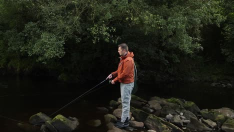 Hand-held-shot-of-a-fisherman-casting-his-spinning-lure-into-a-stream