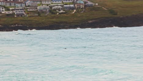 Hand-held-tracking-shot-of-a-surfer-heading-out-into-Fistral-Beach-to-catch-waves