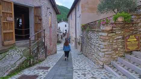 Rücken-Einer-Frau,-Die-Auf-Den-Gepflasterten-Straßen-Des-Mittelalterlichen-Dorfes-In-Rasiglia,-Umbrien,-Italien,-Spaziert