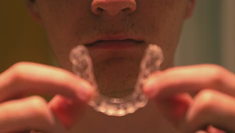 Close-up-shot-of-young-man-removing-his-transparent-Invisalign-retainers-in-the-bathroom