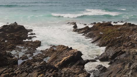 Static-shot-of-small-waves-crashing-against-a-small-rocky-bay-on-Fistral-beach