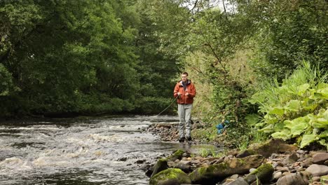 Hand-held-shot-of-a-flyfisherman-walking-and-casting-into-a-small-stream