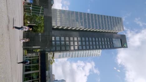Vertikale-Ansicht-Des-Hauptsitzes-Der-Abn-Amro-Bank-Mit-Menschen,-Die-Auf-Den-Zuidas-In-Amsterdam,-Niederlande,-Spazieren