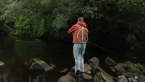 Hand-held-shot-of-a-fisherman-casting-his-spinning-rod-whilst-carrying-a-net