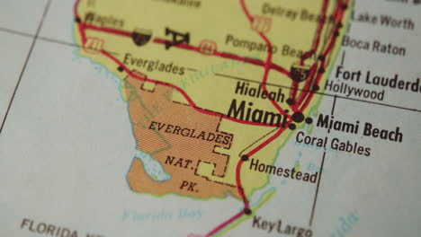 The-camera-pans-across-a-paper-map-of-Florida-and-stops-on-Miami