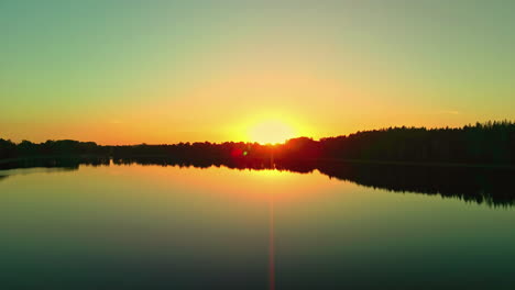 Die-Luftaufnahme-Zeigt-Einen-See-Bei-Sonnenuntergang-Mit-Einer-Baumgrenze-Silhouette-In-Lettland