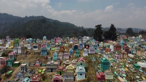 Aerial-rises-over-whimsical,-colorful-crypt-buildings-in-cemetery