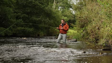 Hand-held-shot-of-a-flyfisherman-wading-and-casting-into-the-river