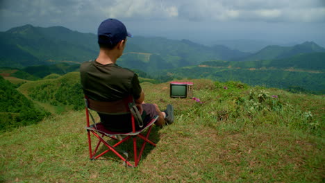 young-man-watches-an-old-analog-television-in-isolation-in-the-mountains