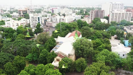 Aerial-view-of-Watson-Museum,-Rajkot,-drone-camera-moving-forward-and-lots-of-parrot-birds-coming-in-front-of-the-drone