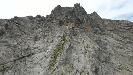 FPV-drone-reaching-the-peak-of-a-steep-rocky-mountain-in-Tyrol,-Austria