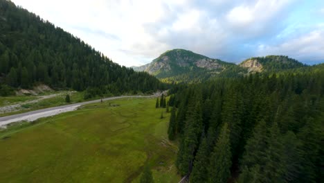 Straße-Umgeben-Von-Naturbelassenem-Alpenwald-In-Einem-Tal-Im-Cadore,-Italien,-Mit-Der-Dolomiten-Bergkette-Im-Hintergrund-Bei-Sonnenuntergang