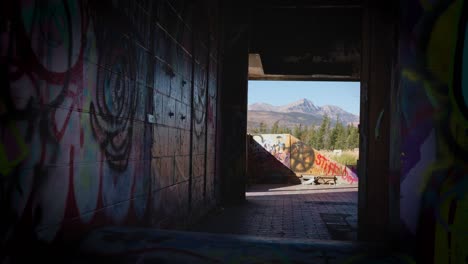 Las-Montañas-Rocosas-Canadienses-A-Través-Del-Graffiti-Pintado-En-El-Pasillo-Del-Edificio-Abandonado-Fort-Chiniki-En-Las-Afueras-De-Canmore,-Alberta,-Canadá