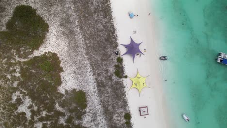 Kites,-camp-awnings-and-surfers-at-Crasqui-Island,-Los-Roques