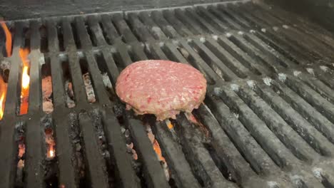 Raw-Hamburger-patty-cooking-on-a-flame-lit-grill