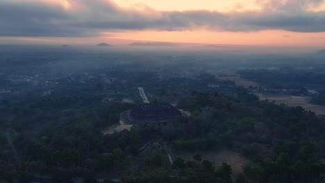 Orbit-Drohnenaufnahme-Des-Borobudur-Tempels-Mit-Magischem-Licht-Des-Sonnenaufgangshimmels-Am-Nebligen-Morgen