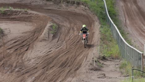 A-slow-motion-shot-of-an-enduro-rider-riding-on-a-motocross-track-approaching-a-high-speed-berm