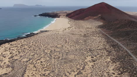La-Graciosa-island:-aerial-view-traveling-out-to-Bermeja-mountain-and-Las-Conchas-beach-on-a-sunny-day-and-turquoise-waters