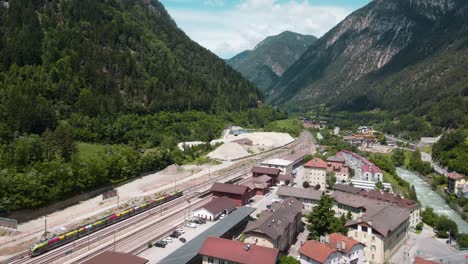 Beautiful-Scenic-View-of-small-Italy-Village-between-Green-Mountains,-near-the-blue-Eisack-river-stream,-tall-bridge-and-train-station---Cinematic-Aerial-Drone-View