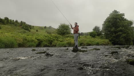 Low-angle-shot-of-a-fisherman-casting-his-flies-into-a-small-stream-trying-to-catch-fish